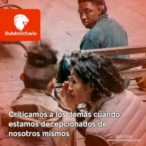 Persona observando a otros mientras escucha una conversación, simbolizando cómo la crítica refleja nuestra decepción interna.