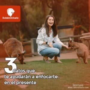 Mujer sonriendo mientras interactúa con canguros, representando presencia y conexión con el momento.