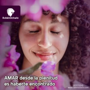 Mujer sonriente con los ojos cerrados entre flores, simbolizando el amor espiritual que nace desde la plenitud interior.