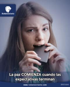 Mujer ansiosa mordiendo su teléfono, simbolizando cómo las expectativas generan tensión emocional.