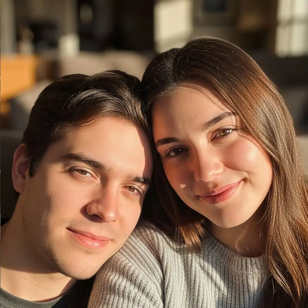 Pareja joven sonriendo en casa, luz cálida del atardecer, simbolizando el amor consciente y la conexión emocional que florecen al sanar desde el interior.