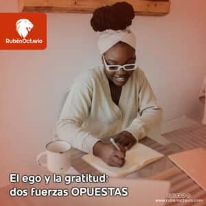 Mujer escribiendo en su cuaderno con una sonrisa, simbolizando la práctica de la gratitud frente a las distracciones del ego.