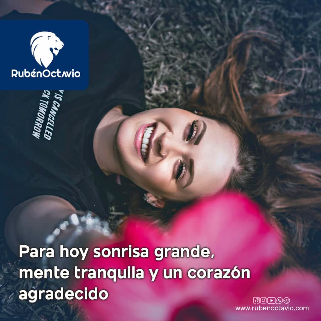 Mujer sonriendo acostada en el césped representando paz, gratitud y alegría.
